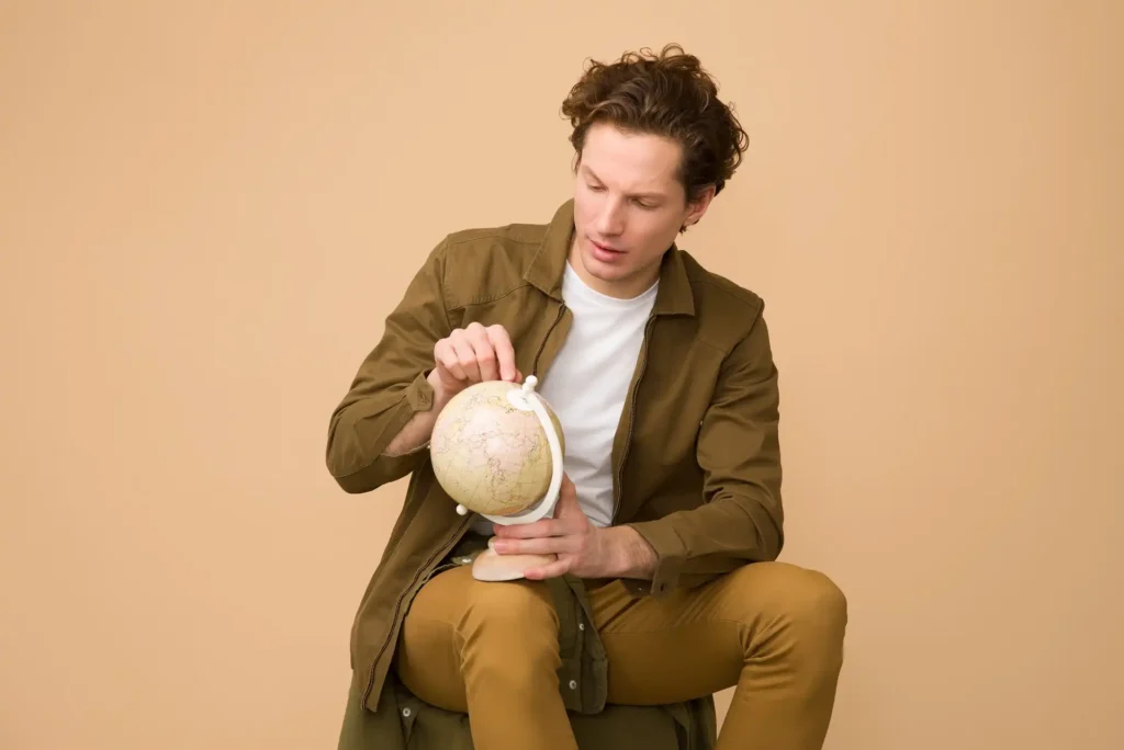 In the picture, a close-up of a man looking at a globe.